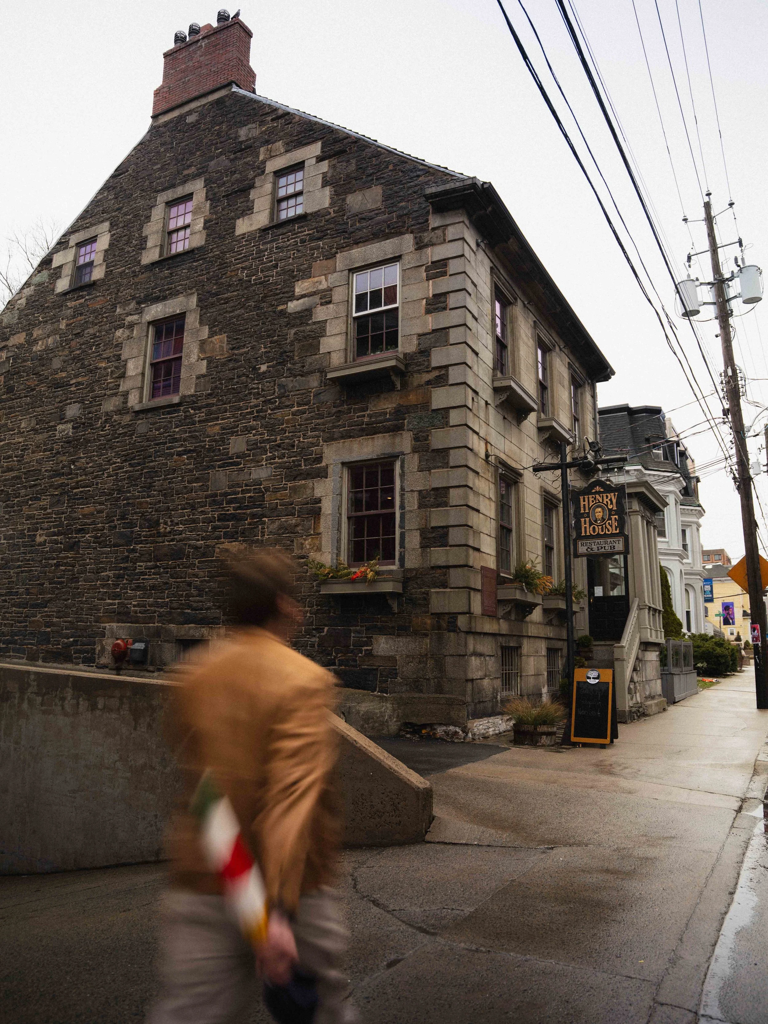 outside the Henry House Restaurant & Pub in Downtown Halifax, Nova Scotia on a moody day. Man is motion blurred walking past down the sidewalk