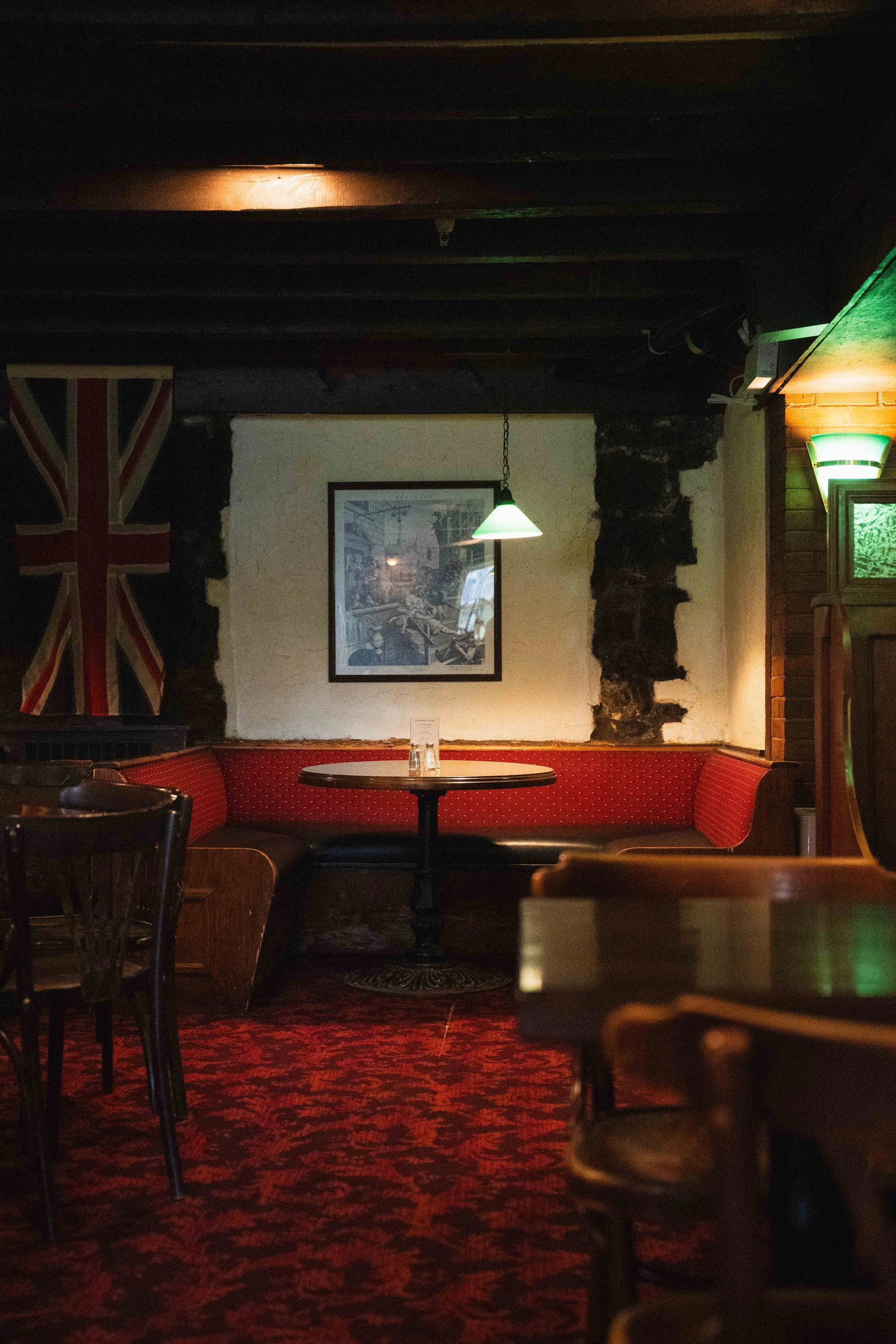 a basement pub with stone walls, a british flag hanging, and historic red booths with a cozy fireplace, dart board, and ambient lighting in Halifax, Nova Scotia