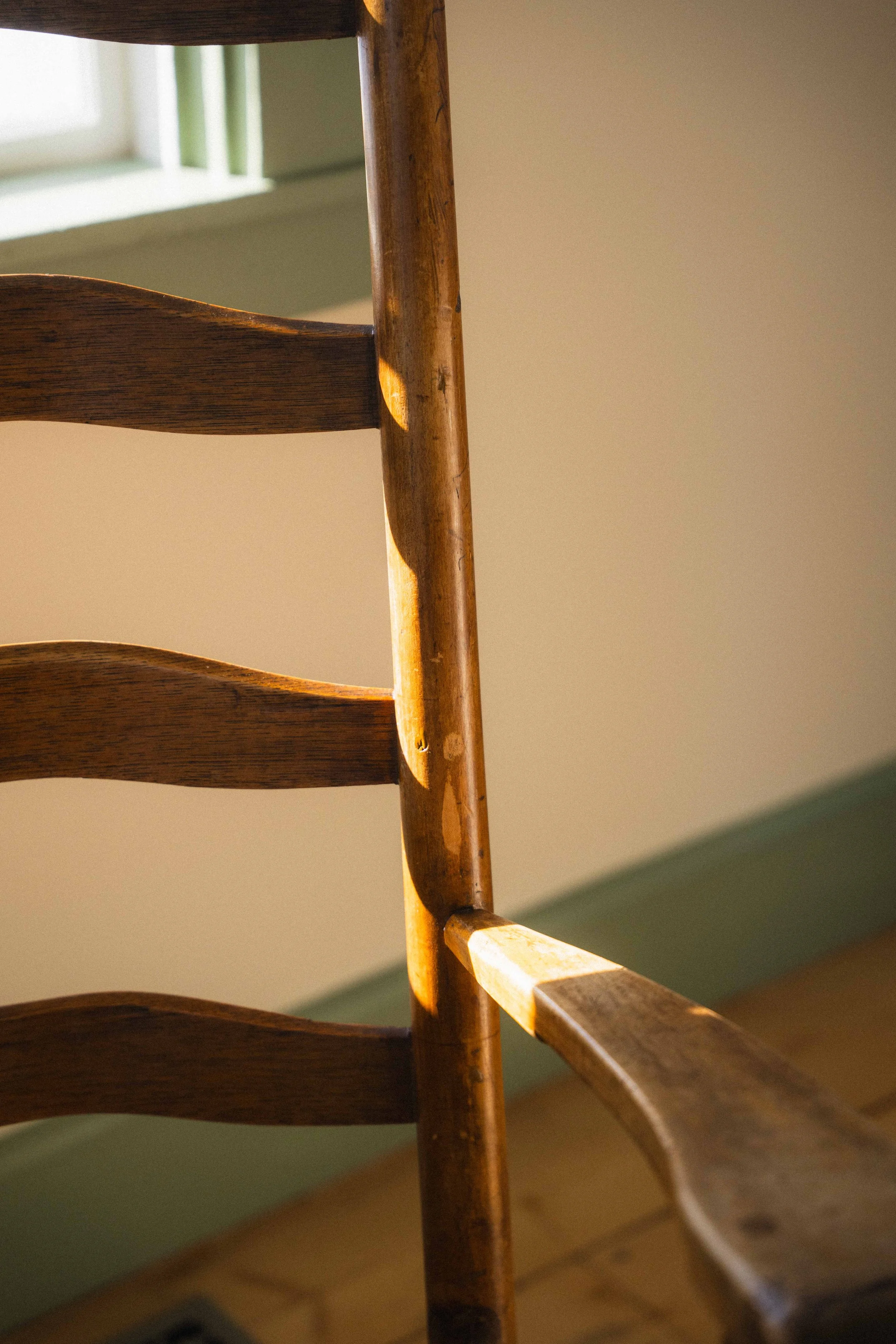 cottagecore home decor with an antique wooden ladder back rocking chair and green painted trim and cream walls