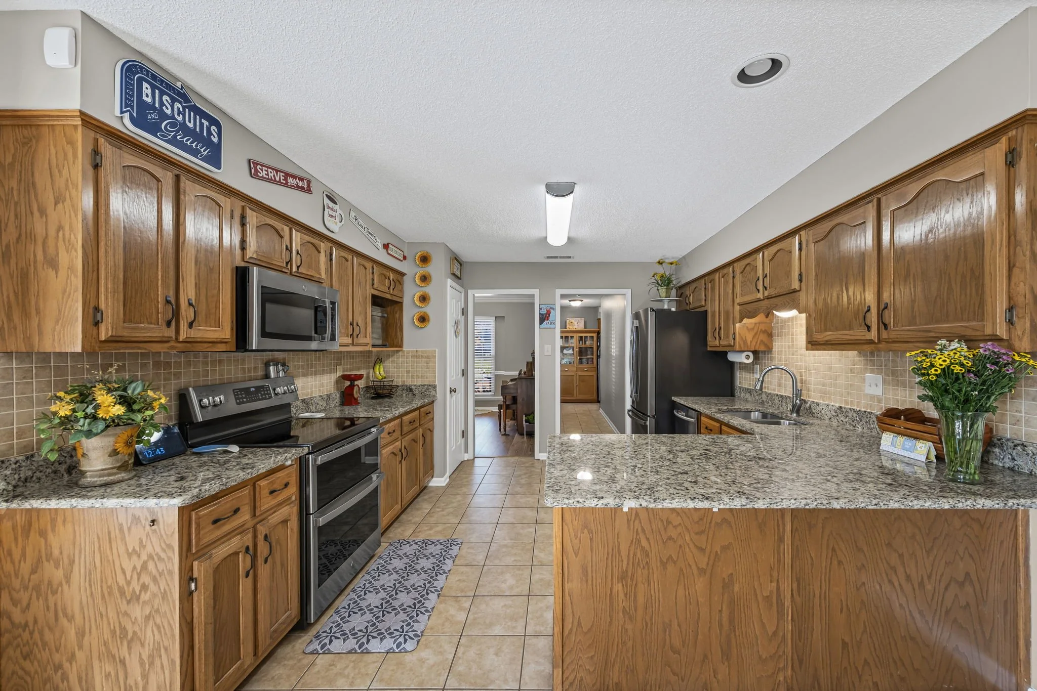 Light filled kitchen with granite countertops, backsplash, microwave, oven
