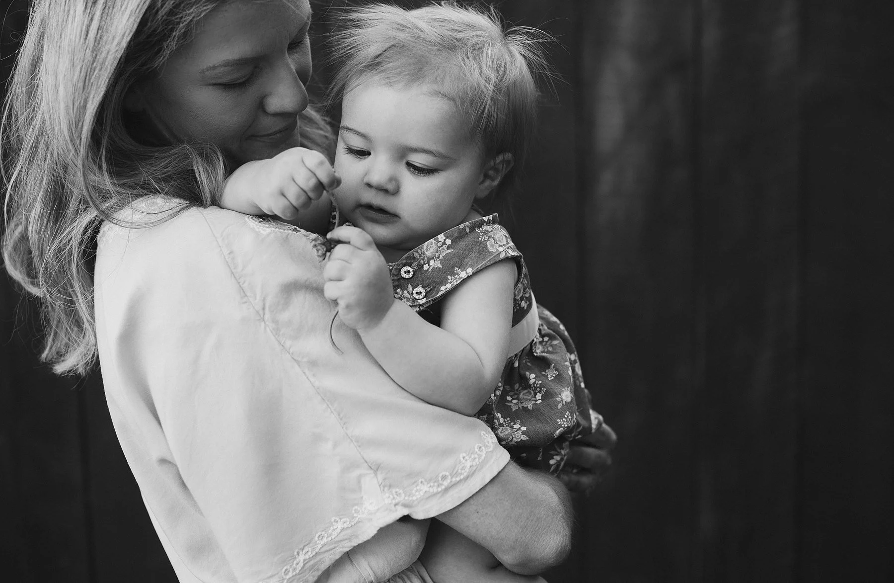 Kate's client, Emily holding her baby in front of an old wood barn