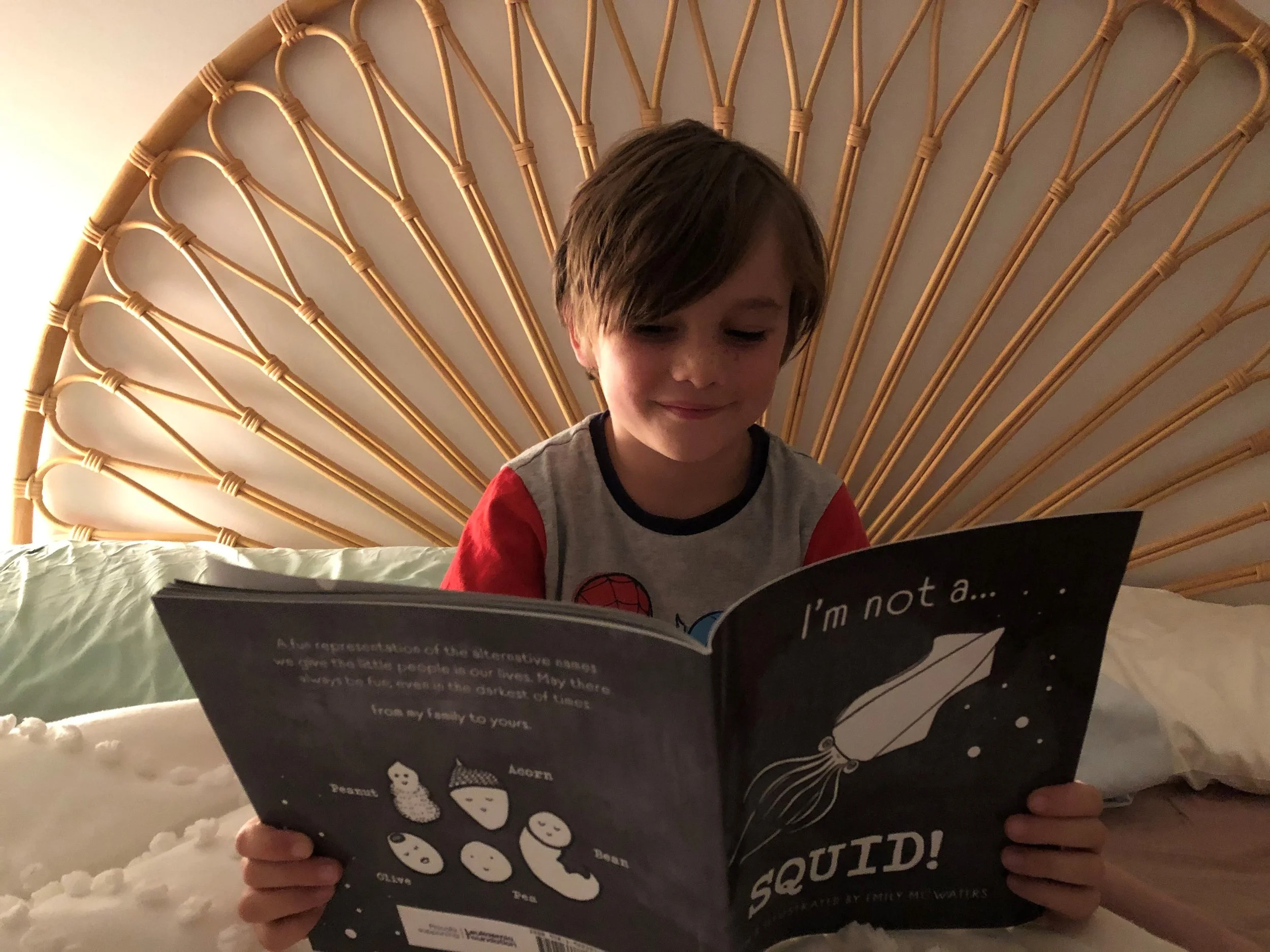 Young boy sitting in bed, reading I'm not a SQUID!