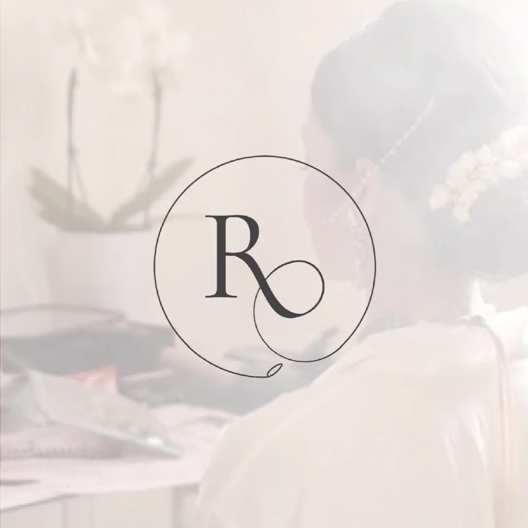 A logo with a circle and block letter 'R' inside, featuring a stylized dark swirl extending from the bottom of the 'R'. In the background, there is a blurred image of a woman working at a desk with a plant and a pair of glasses.