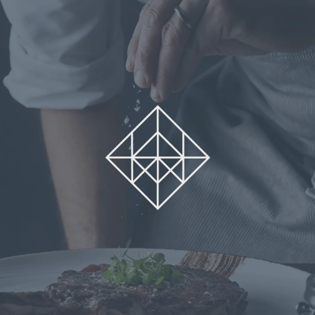 Chef seasoning a steak with salt, with a geometric logo overlay "With a Pinch of Salt"