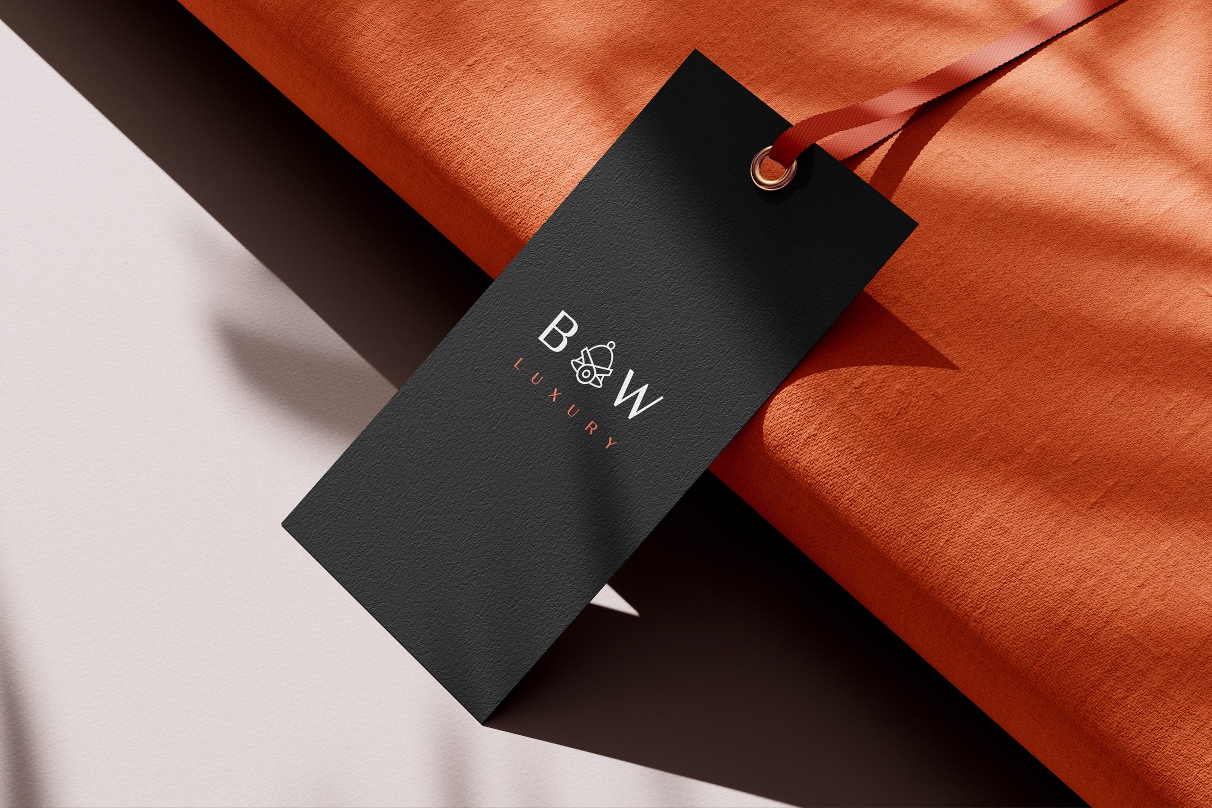 Close-up of a luxury gift box wrapped in orange paper with a black tag attached, bearing the logo and name of Bells & Whistles Luxury.