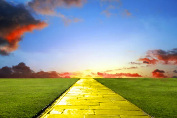 Glowing Yellow Brick Road Traveling through Green Grass under a Blue Sky