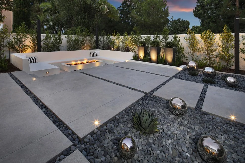 Custom outdoor living space featuring firepit, concrete hardscape, and landscape design