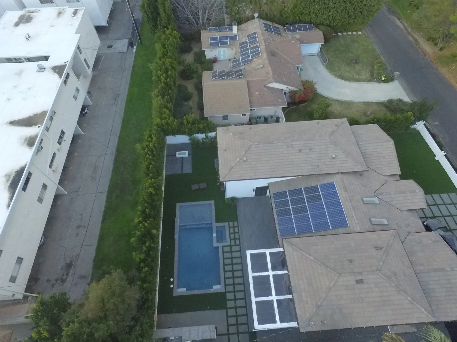 Modern outdoor living space featuring pool, deck, concrete patio, and turf installation
