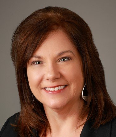 Professional woman with shoulder-length brown hair smiling at the camera