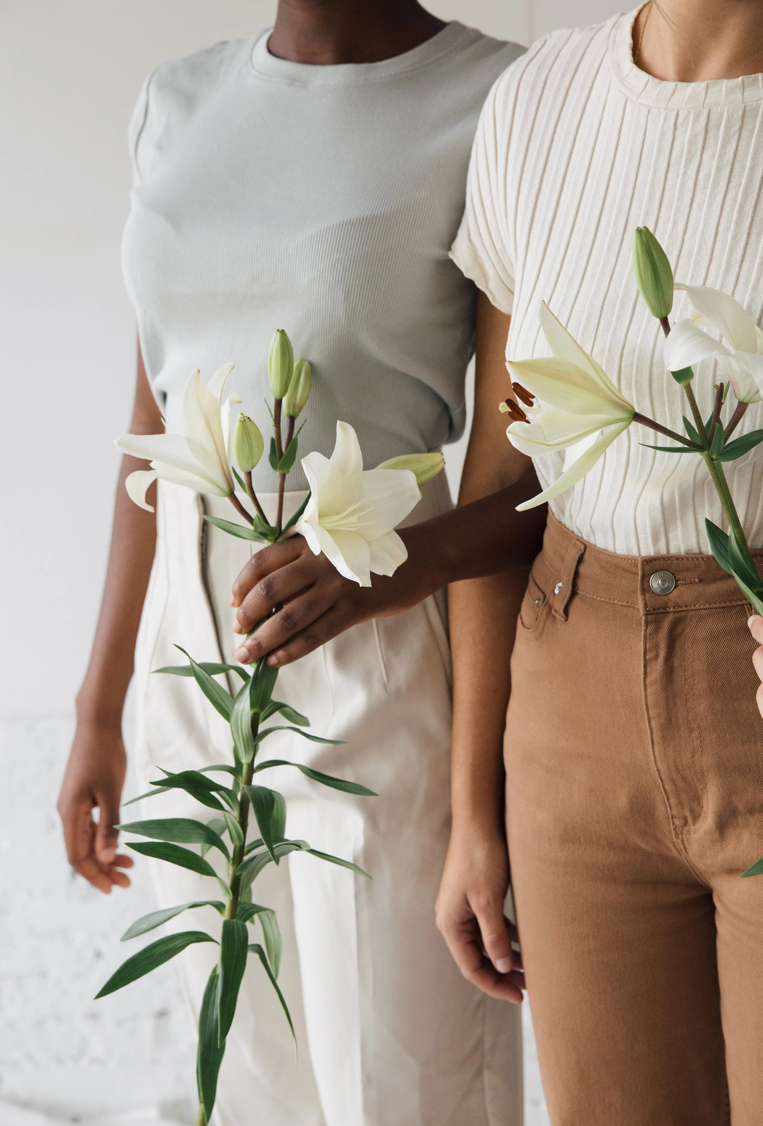 Two female presenting people holding white flowers