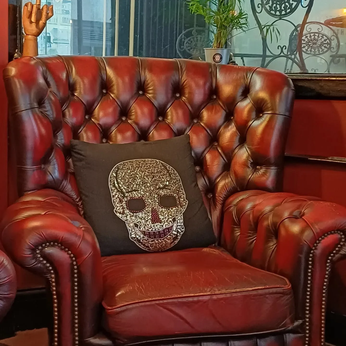 A Chesterfield leather armchair with a skull cushion resting on it