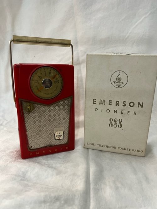 Red Emerson Eight Transistor Radio with gold dial and gold handle. Sitting on a white sheet.
