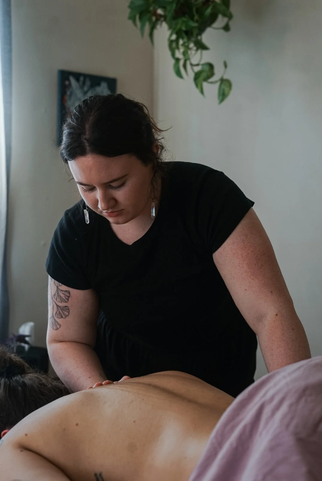 A woman giving a massage to a person lying face down on a massage table.