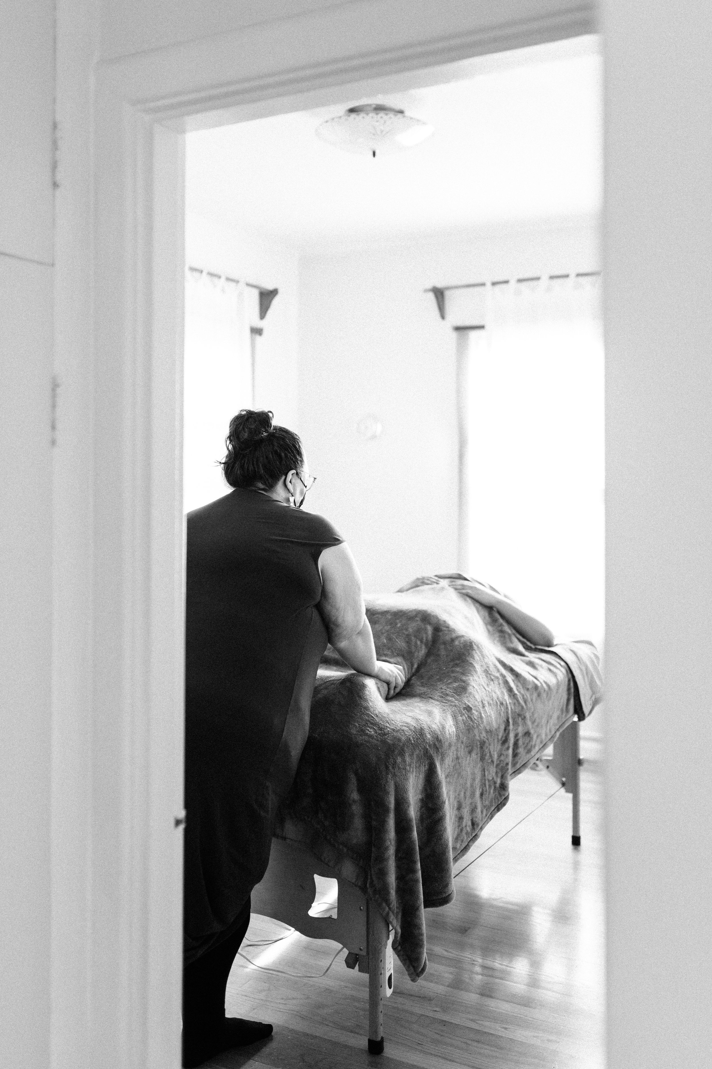 A person giving a massage on a massage table in a softly lit room.