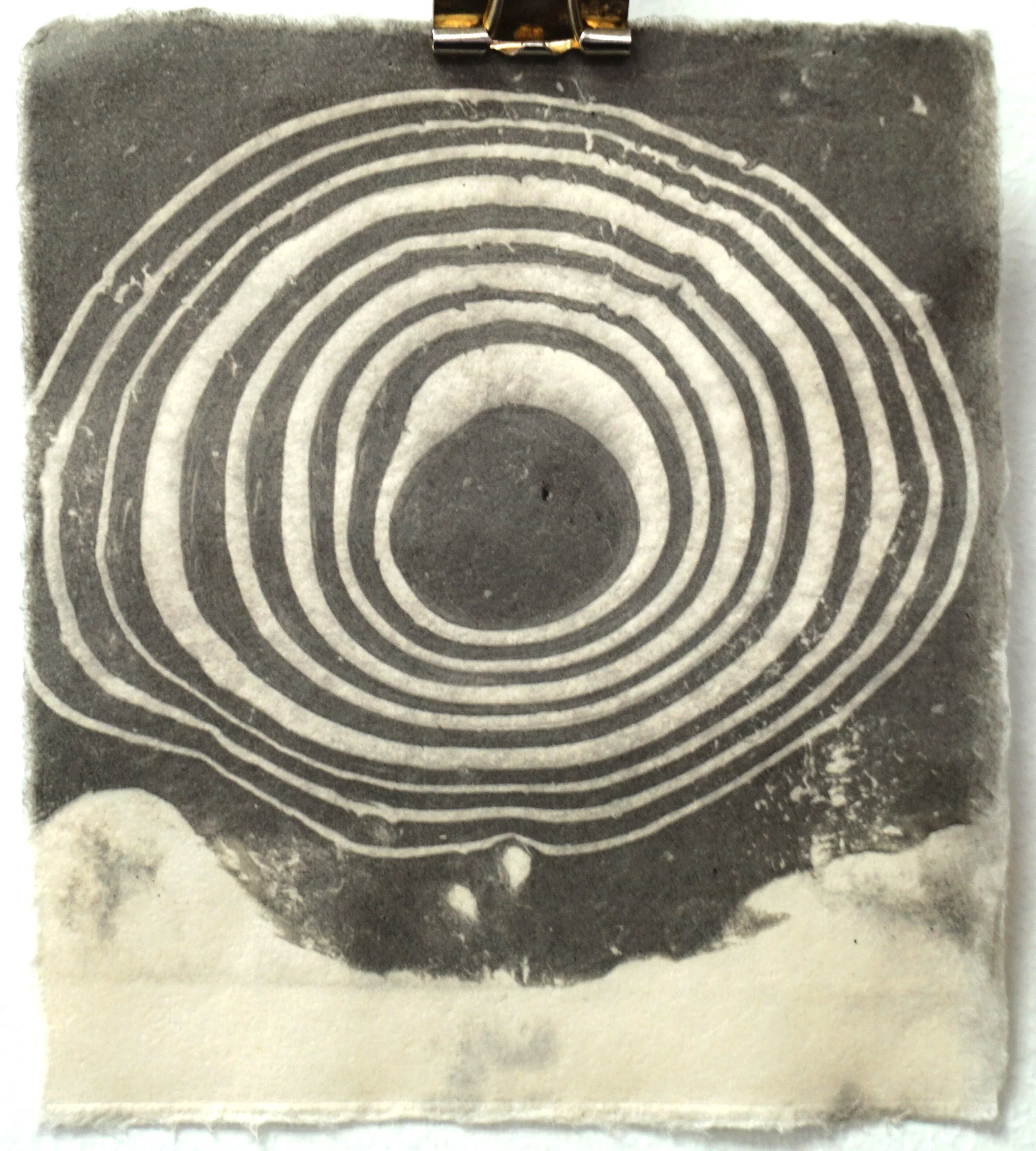 A black and white illustration of a cross-section of a tree trunk showing growth rings, with some clouds at the bottom.