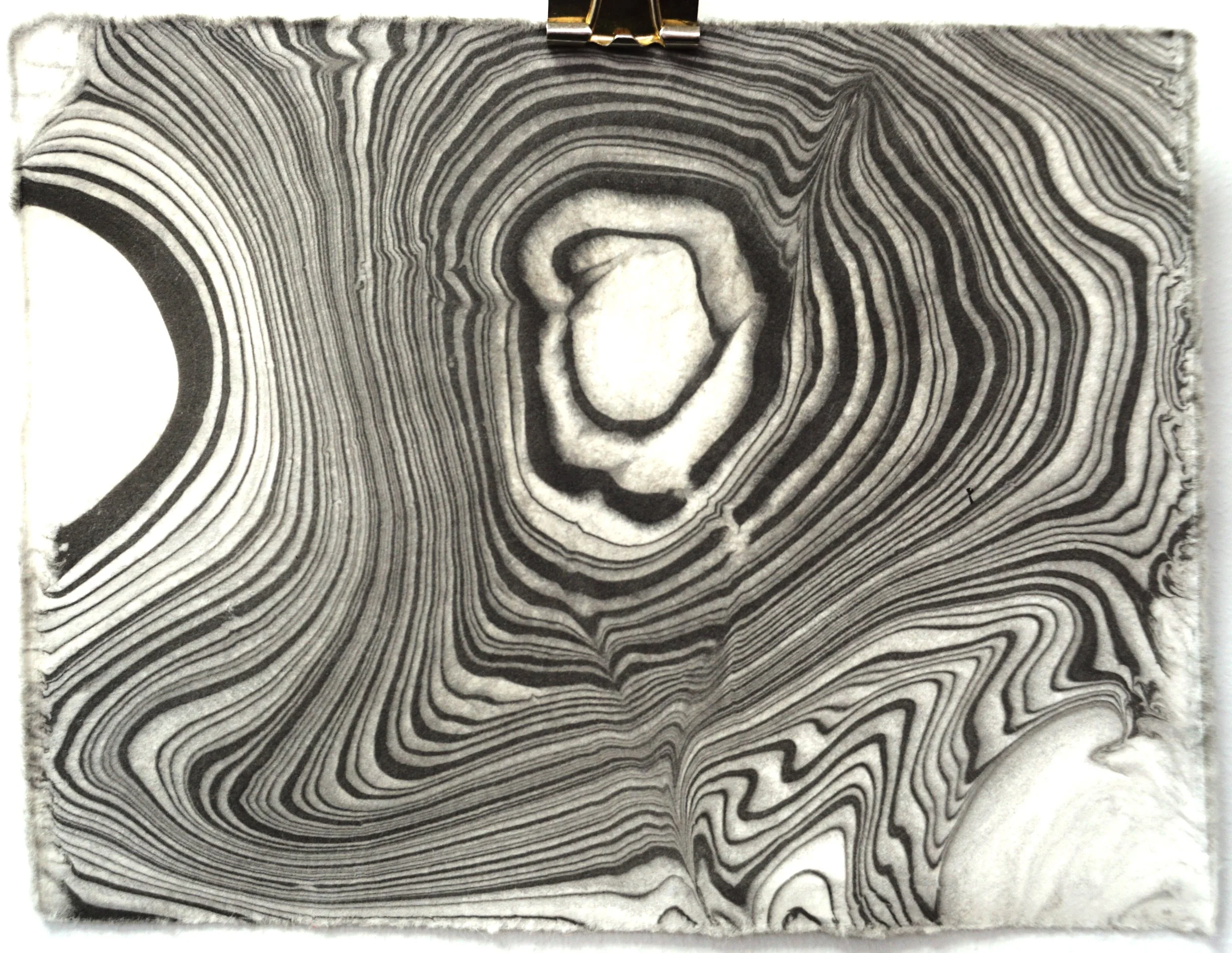 Close-up of a layered rock formation with concentric lines and a central crater-shaped feature.