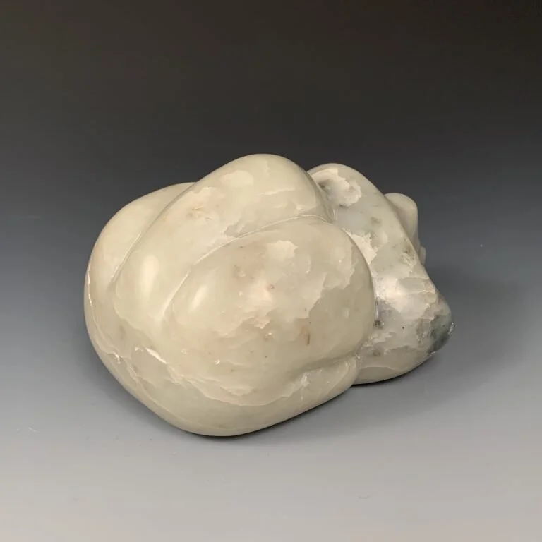 Side rear view of a bear lying down, hand carved from soapstone.