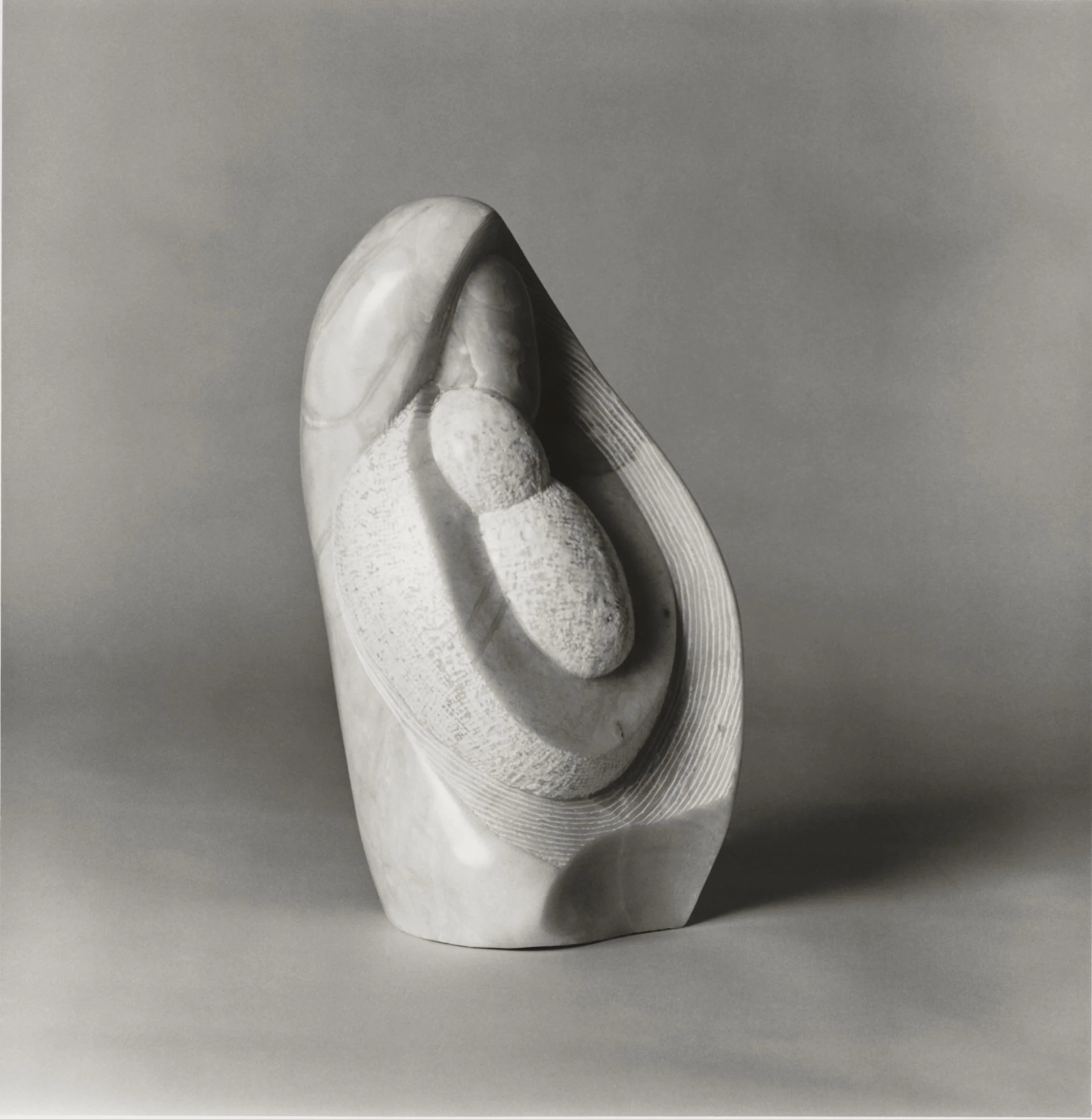 An alabaster abstract sculpture of a woman holding a child.