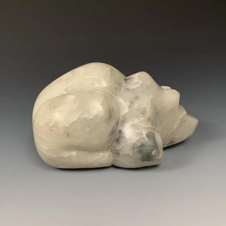 Oppisite profile view of a bear lying down,  sculpted from soapstone
