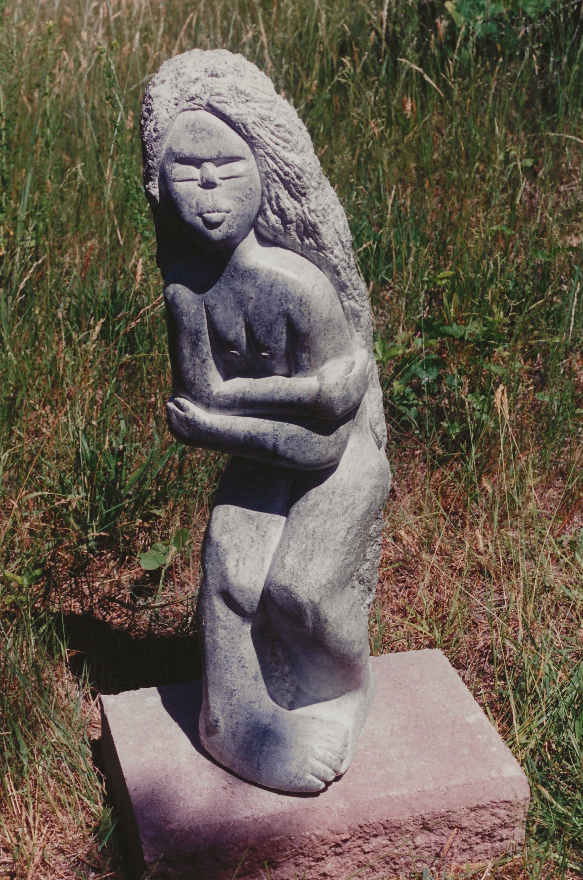 A larges soapstone statuary of woman shivering outside in the cold