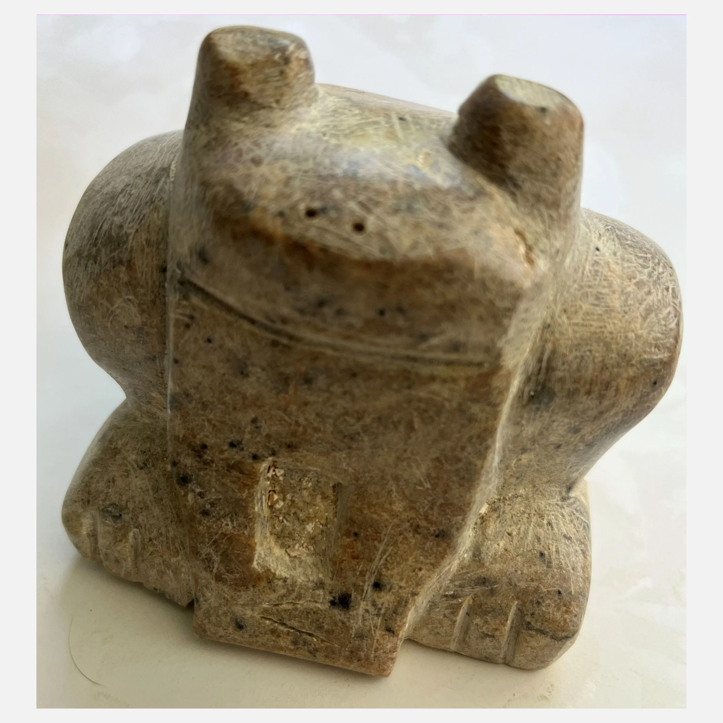 A talc brownish carving of a almost smiling frog