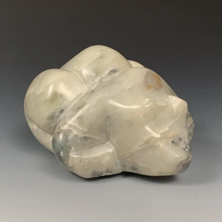 Front view of a hand crafted soapstone bear lying down