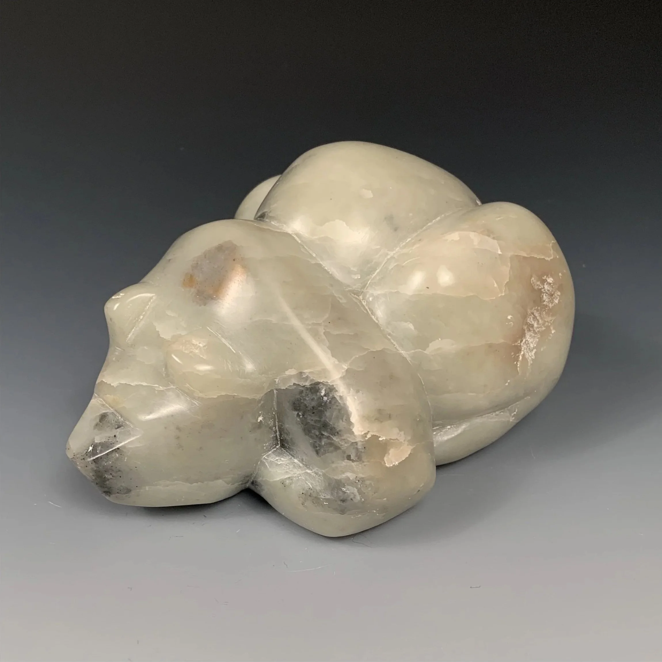 Front view of a sculpted stone bear laying down