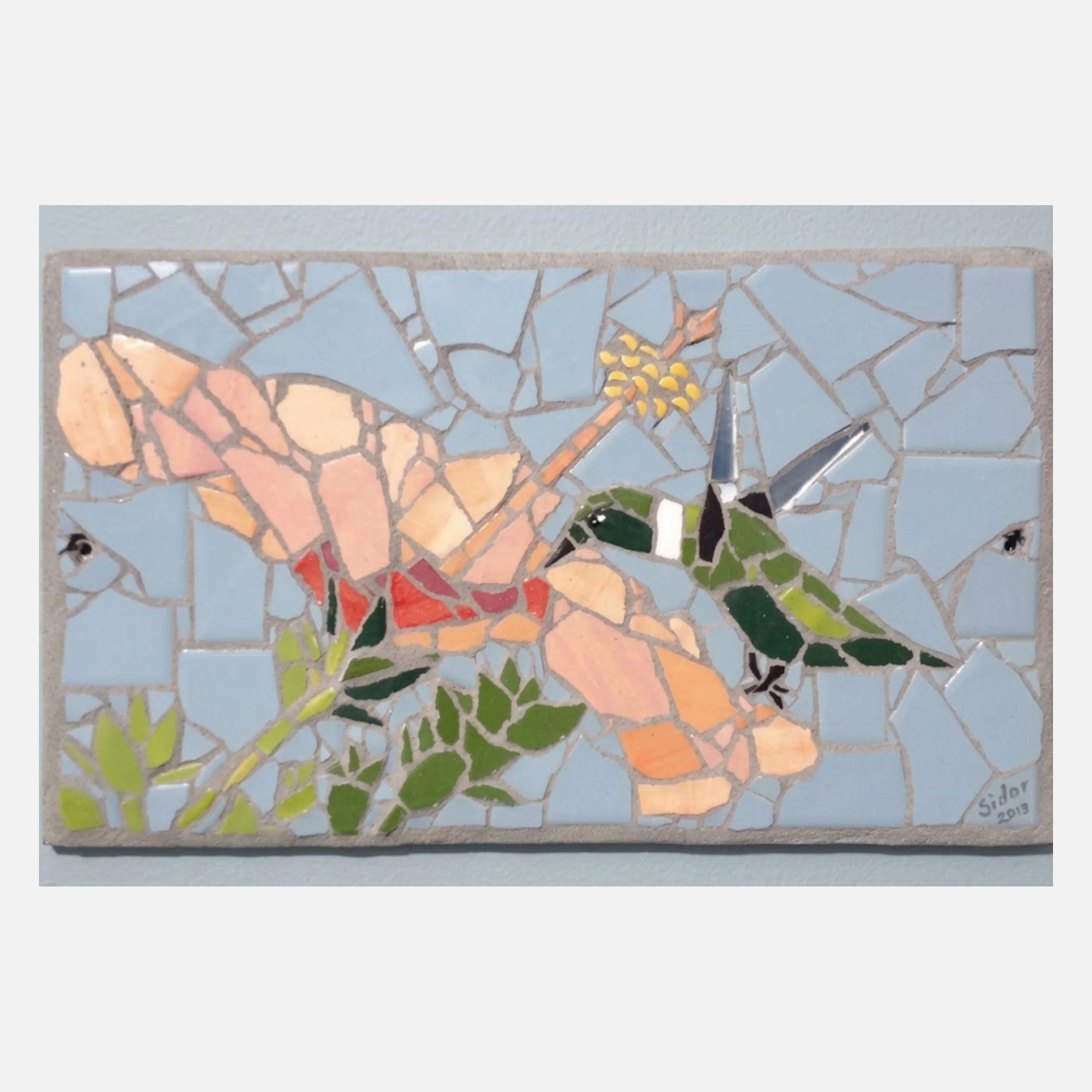 A mosaic of a hummingbird sipping nectar from a orange flower.