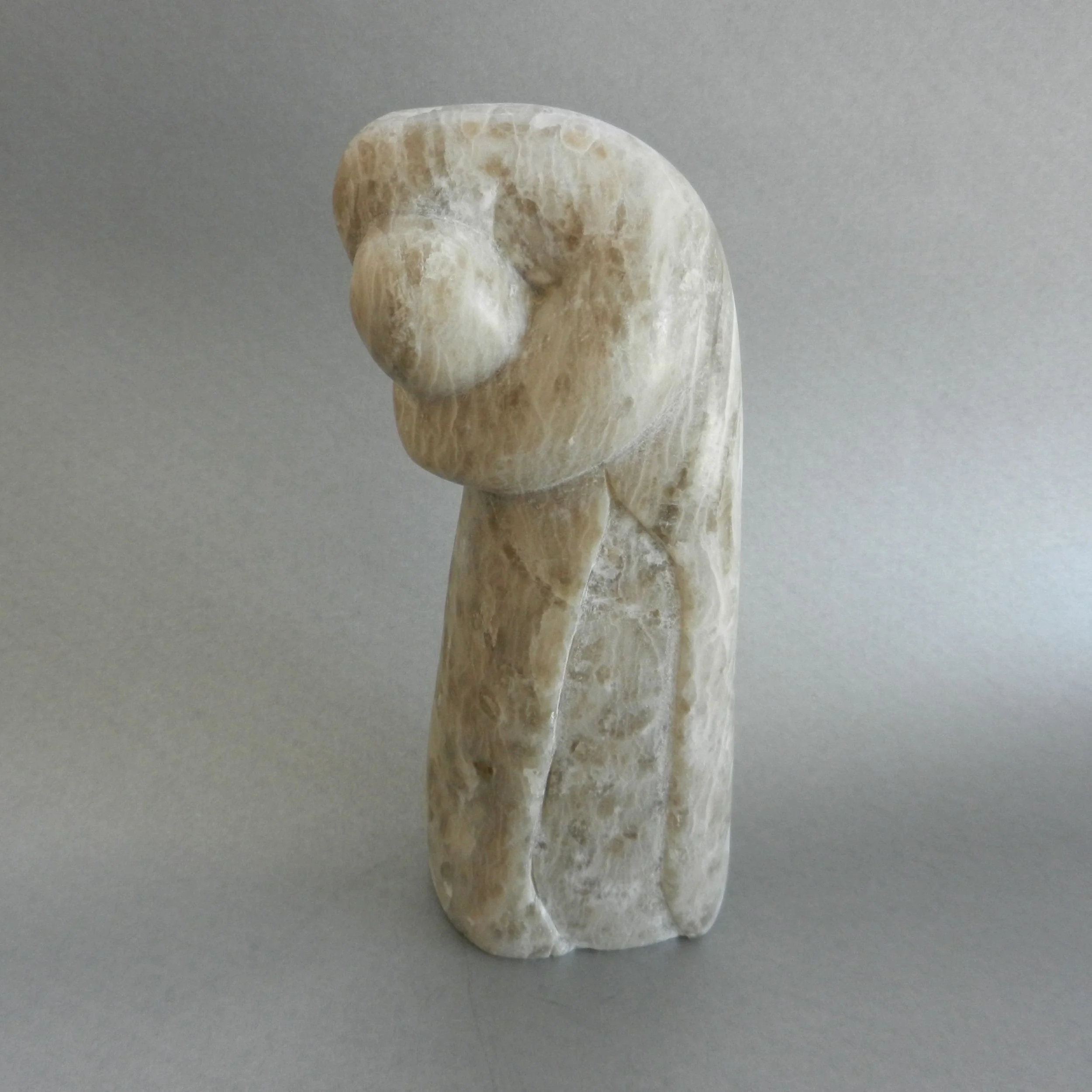 An abstract image of a woman embracing a baby, hand hewed from alabaster.