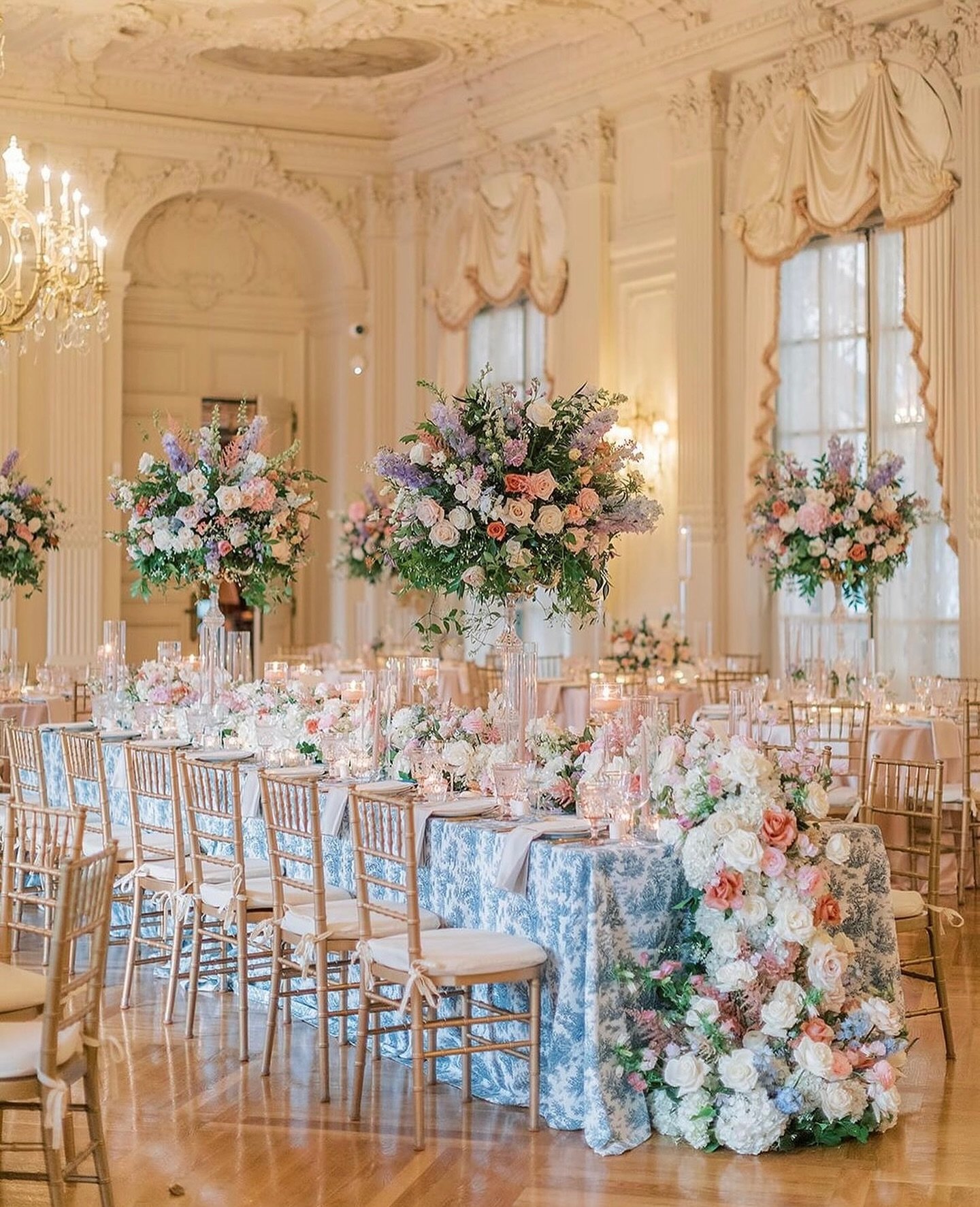 We love the grandeur of a wedding at Rosecliff mansion, where every table is adorned with stunning blooms. For this wedding, shades of pink and lavender florals complemented the elegant charm of vibrant blue and white linens. It was a scene straight 