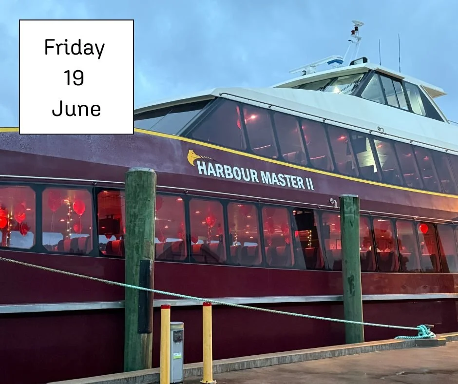 A red boat at a wharf decorated for an event with red lights and decorations