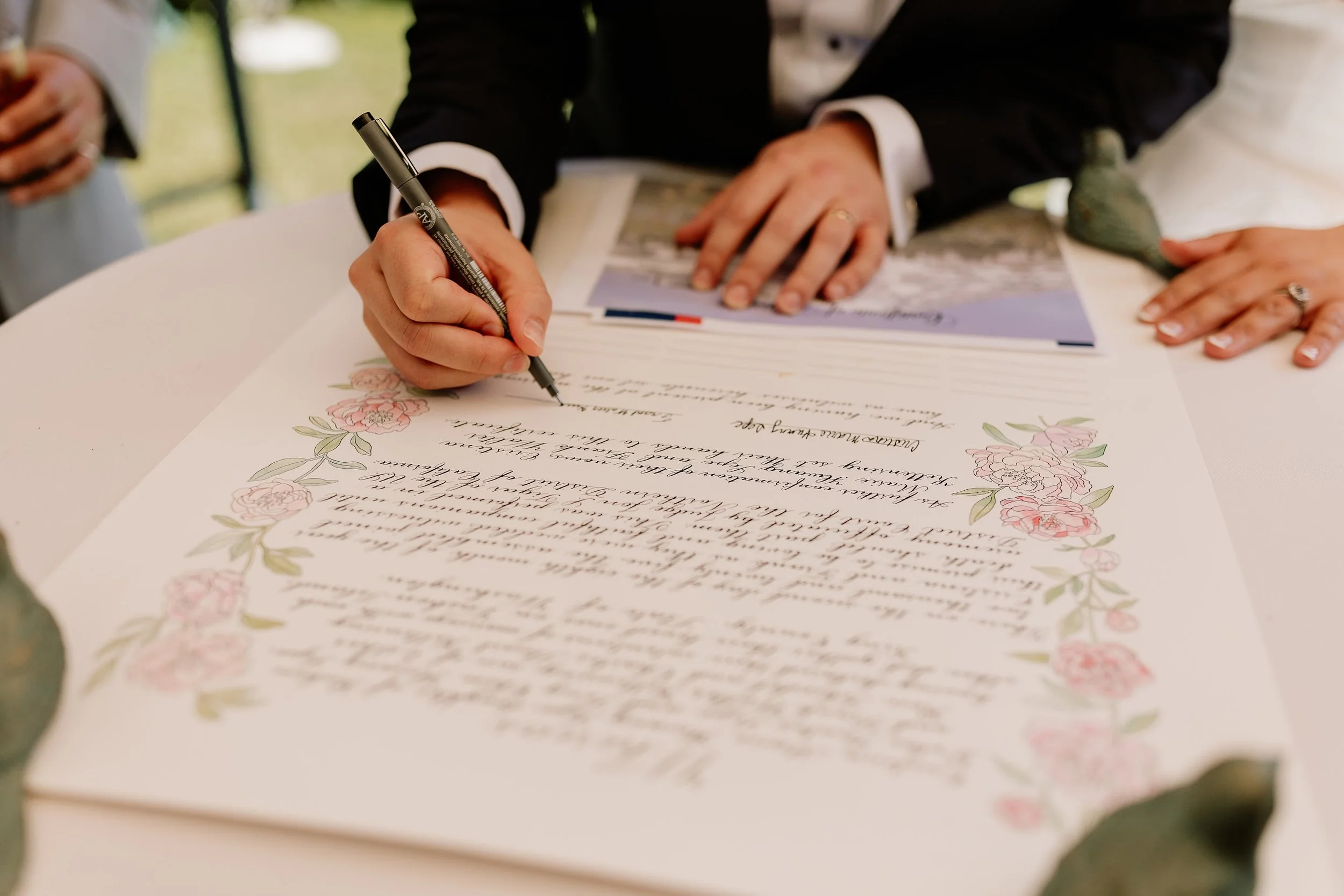 a groom signing a Quaker style marriage certificate with a floral border
