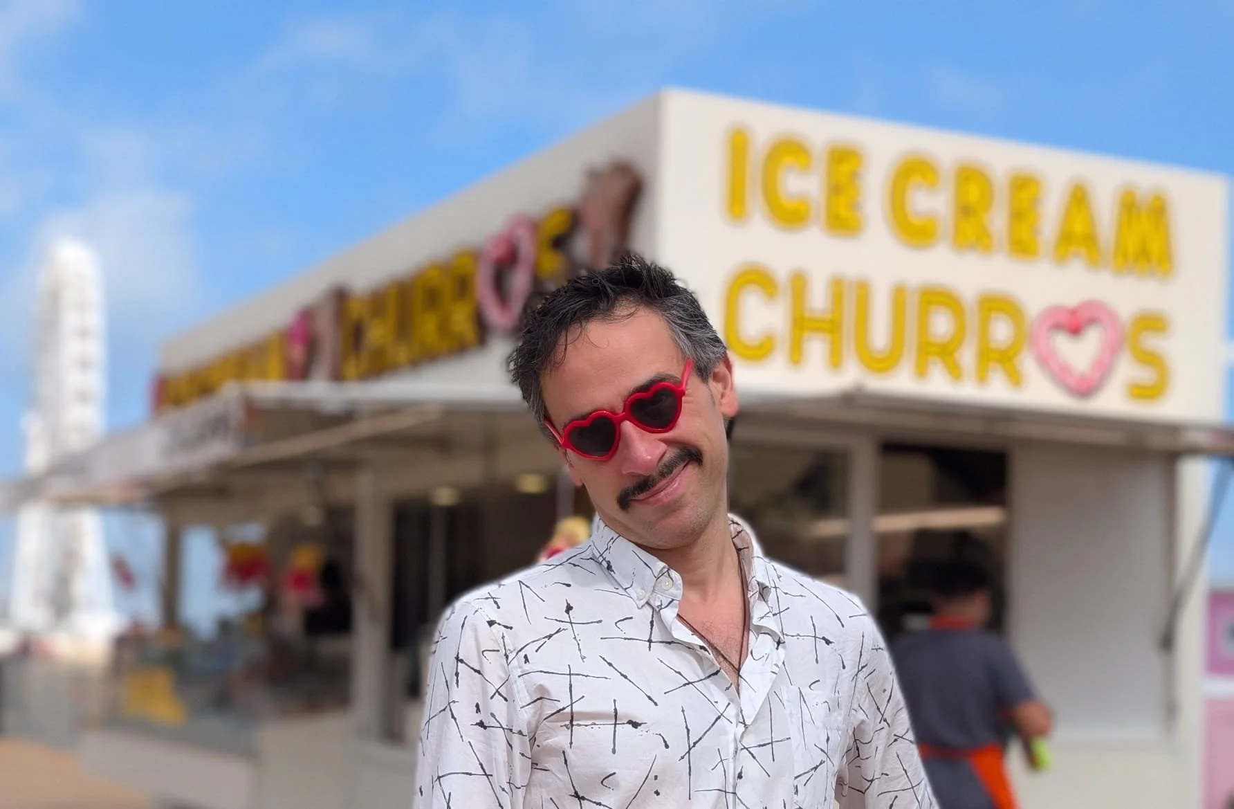 Photograph of David Labi wearing children's sunglasses in front of a Churro stand in Ostend