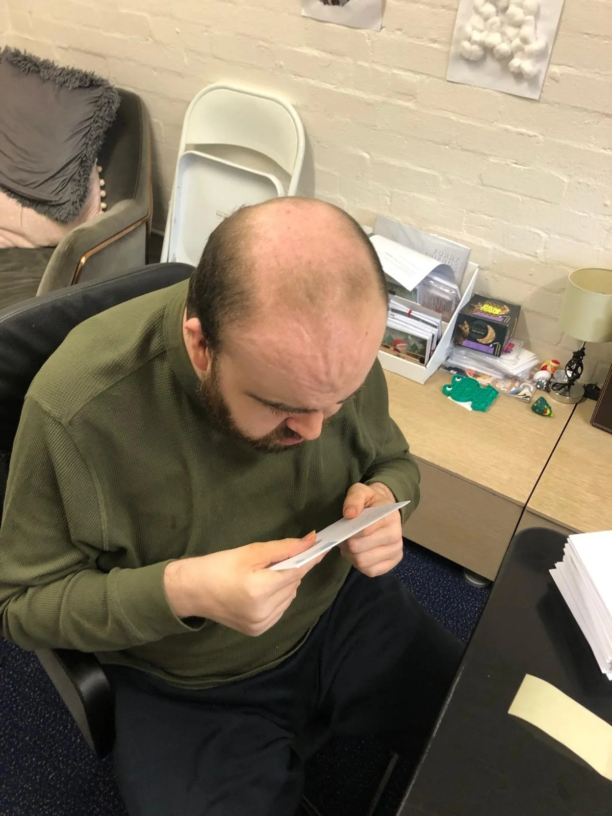 A man sitting at a desk, looking at a piece of paper.