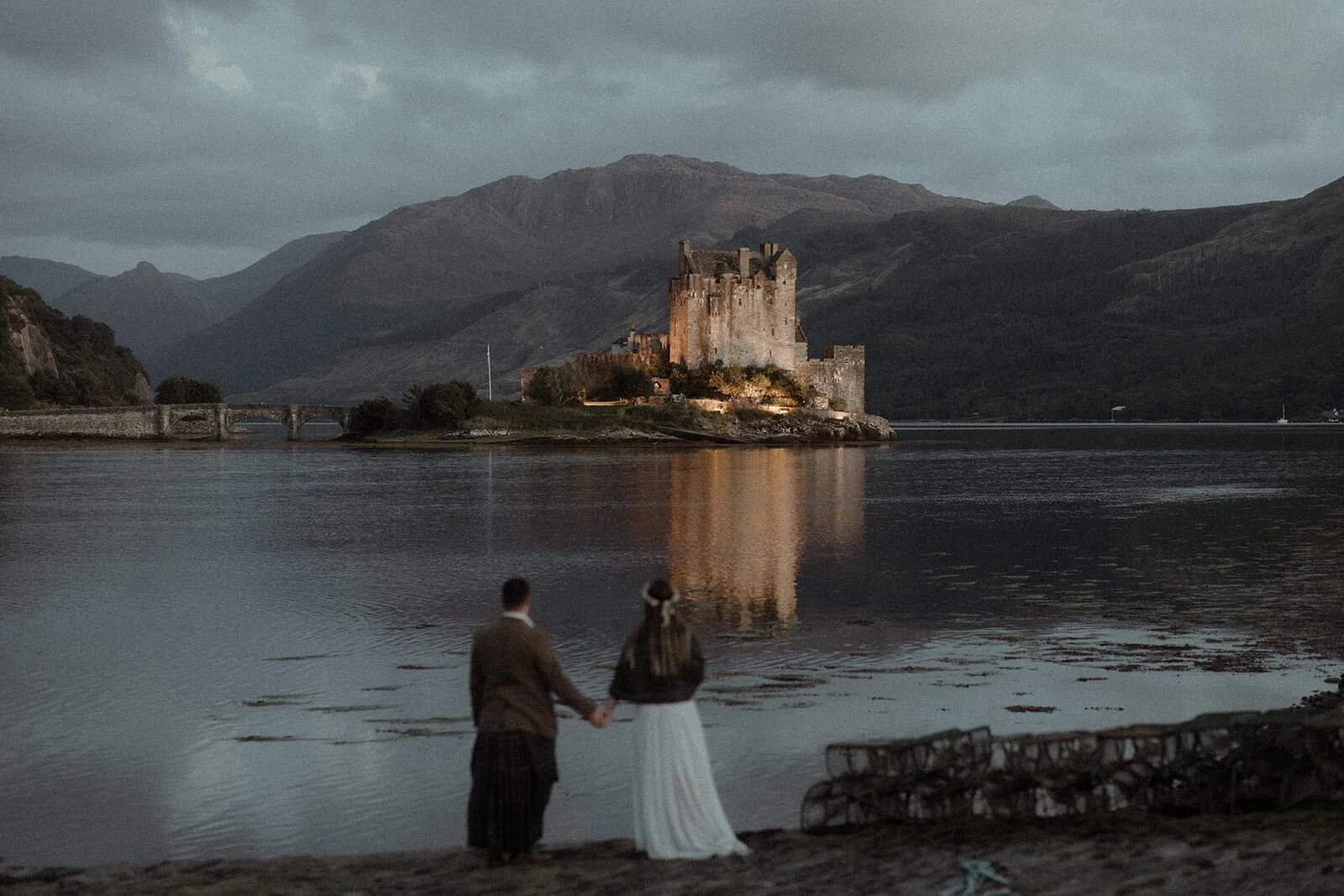 Married couple enjoyes the view of the Eilean Donan Castle in Scotland on their elopement