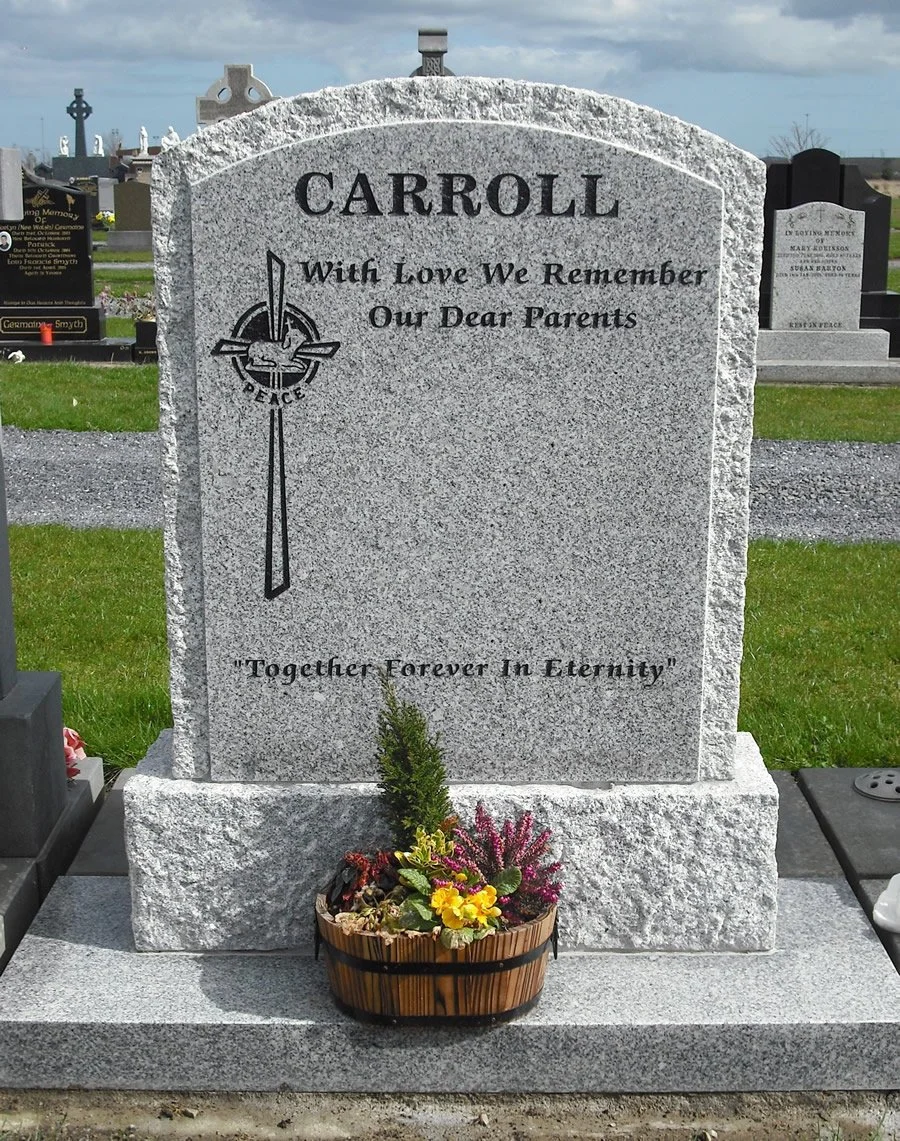 Gravestone for a person with the words "With Love We Remember Our Dear Parents" and the quote "Together Forever In Eternity." The gravestone has a peace symbol with a cross and a dove, and there is a flower arrangement at the base.