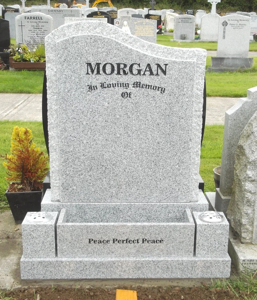 Gray granite headstone with the name 'Morgan' and the phrase 'In Loving Memory Of' and 'Peace Perfect Peace' engraved on it, located in a cemetery.