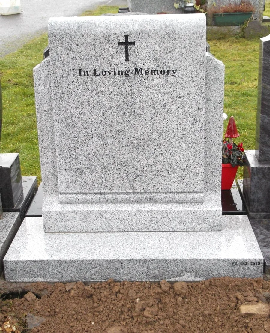 Gray granite headstone with a cross at the top and the inscription 'In Loving Memory'.