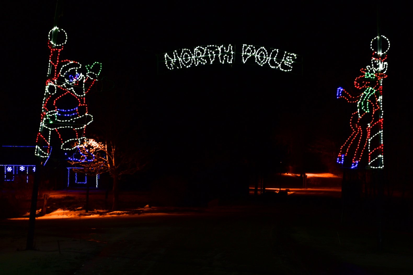Christmas light display with illuminated figures of Santa Claus and a reindeer, and a sign that reads 'NOËL VOUS' in the dark night.