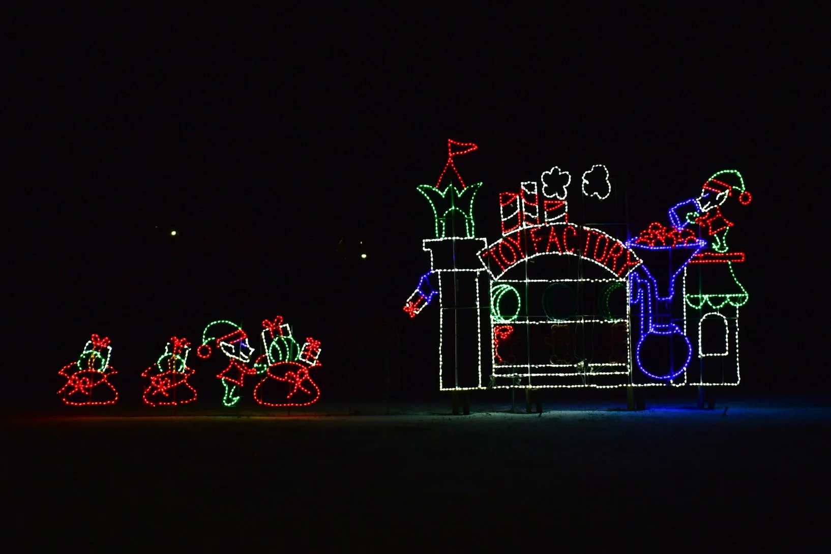 Colorful Christmas light display with Santa, elves, and toys at Toy Factory.