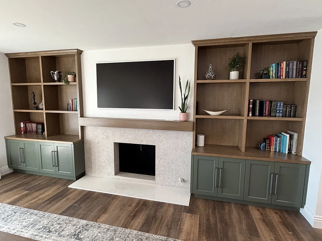 Living room entertainment center with built-in wooden bookshelves, a flat-screen TV, a fireplace, and decorative items.