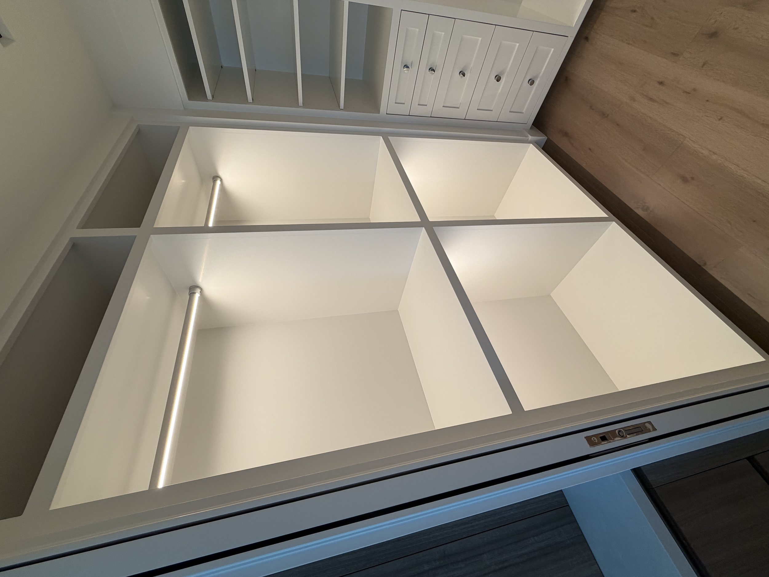 An elevator door opening to reveal a white interior with empty shelves and space for storage.
