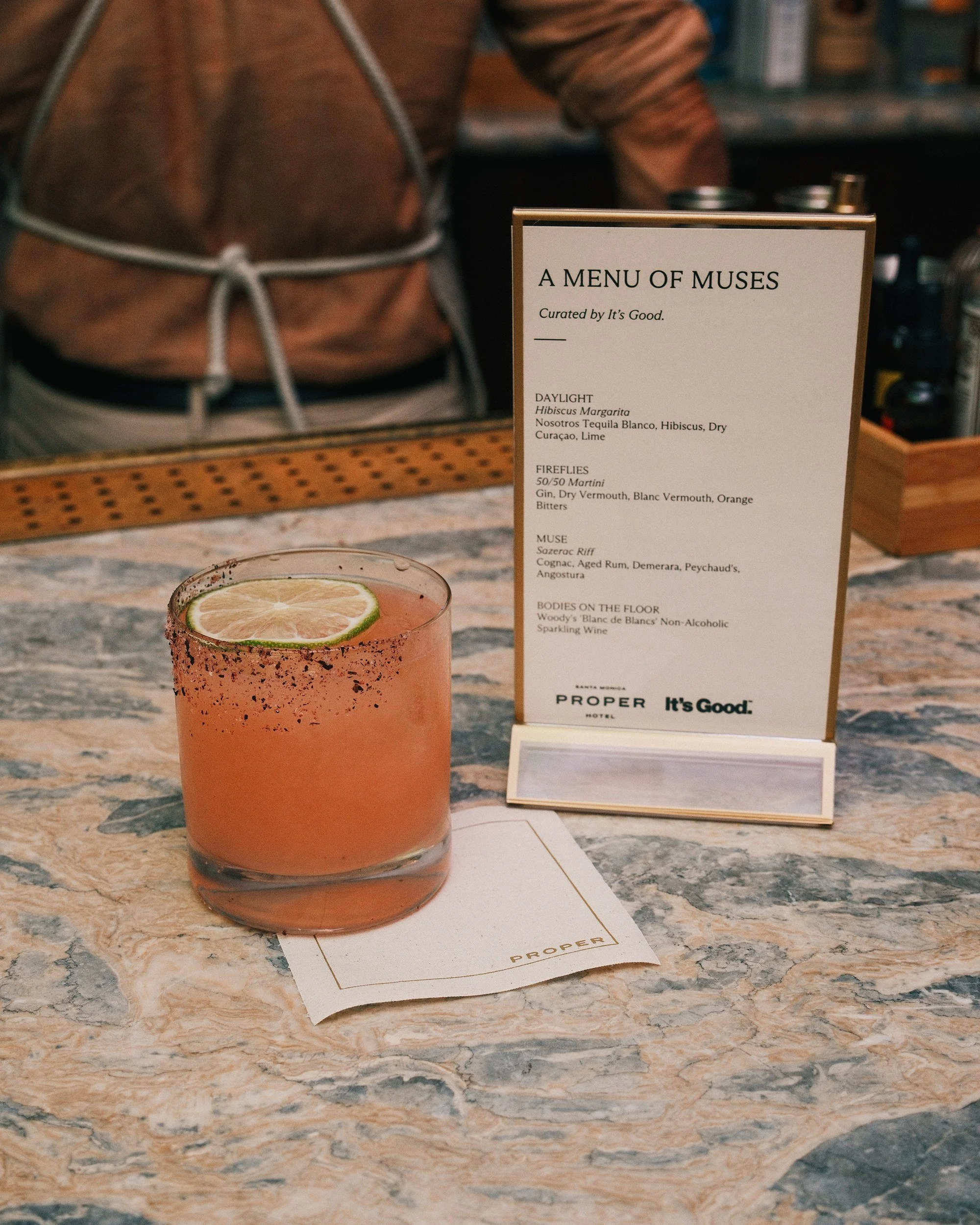 Cocktail and A Menu of Muses card on the bar at Santa Monica Proper