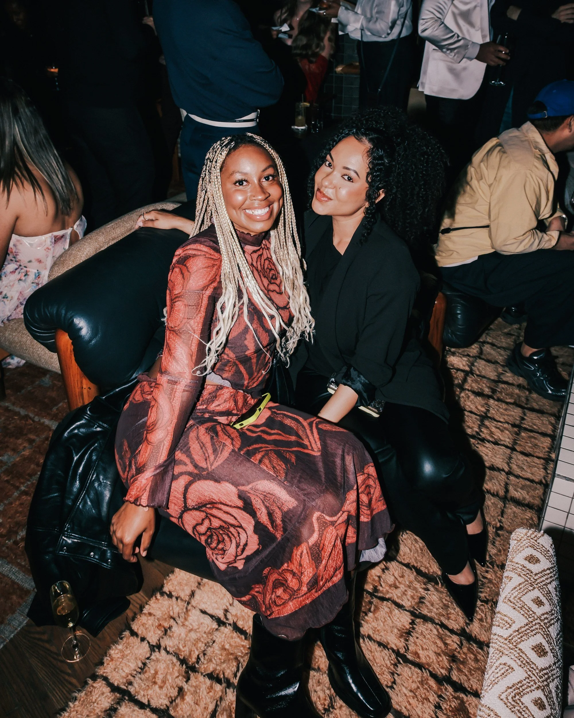 Two guests on a leather chair at John Legend's album release party