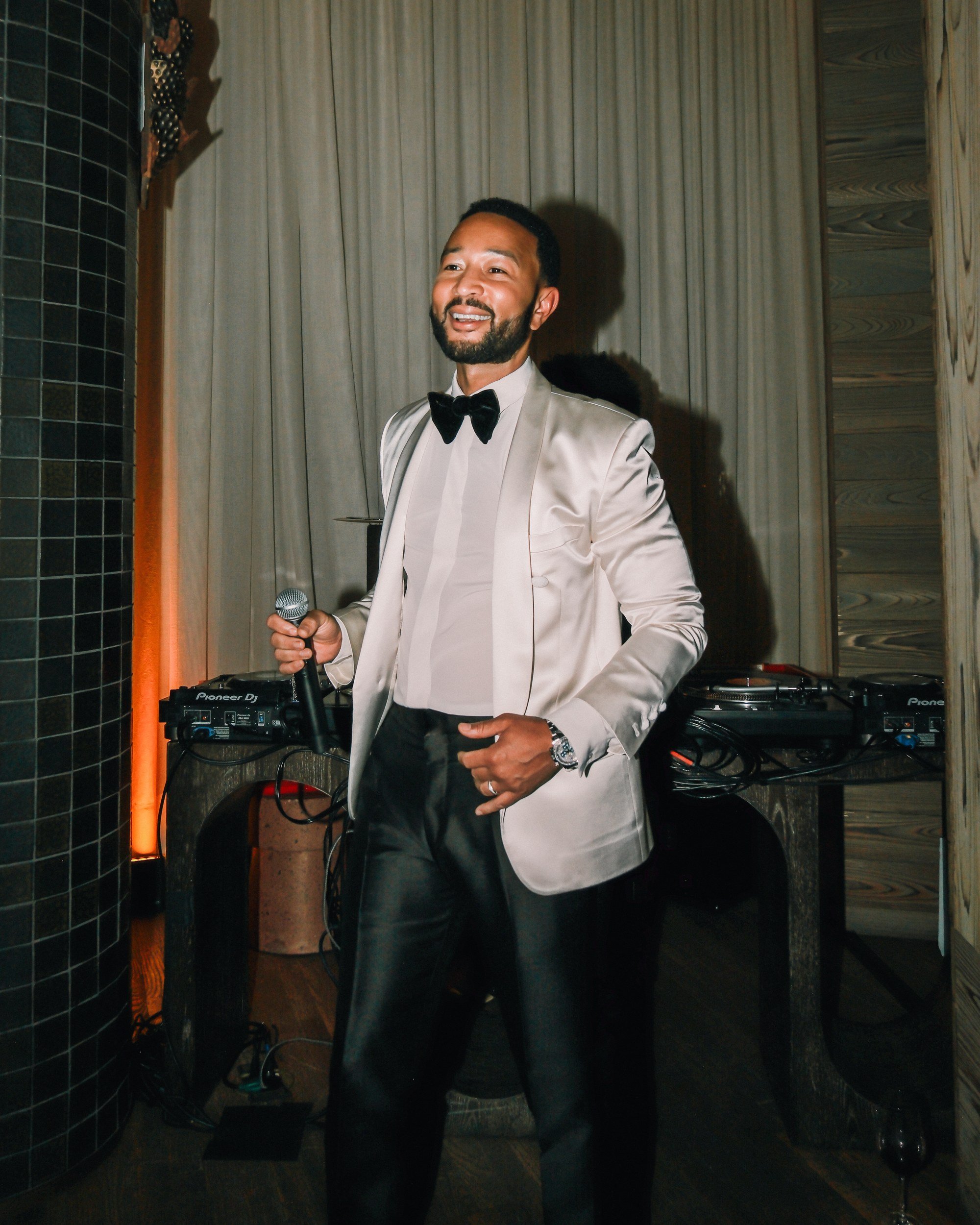 John Legend laughing with a microphone at his album release party