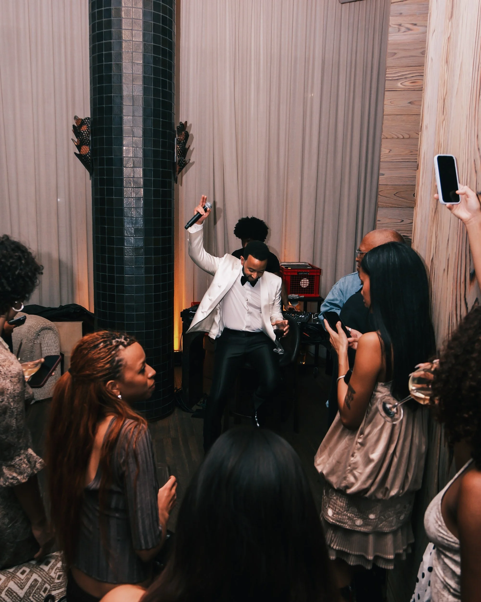 John Legend raising his arm over the crowd at his album release party