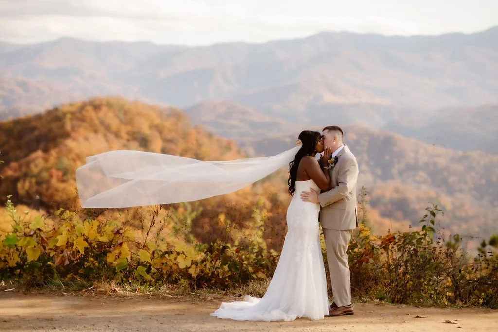 Bride and groom sharing a kiss at scenic mountain overlook with flowing veil, foothills parkway elopement photography capturing intimate fall wedding in the Smoky Mountains by a gatlinburg photographer specializing in outdoor elopements