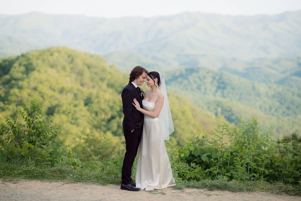 Newlyweds stand together at a mountain overlook during their foothills parkway elopement, surrounded by expansive views of the Smoky Mountain foothills.