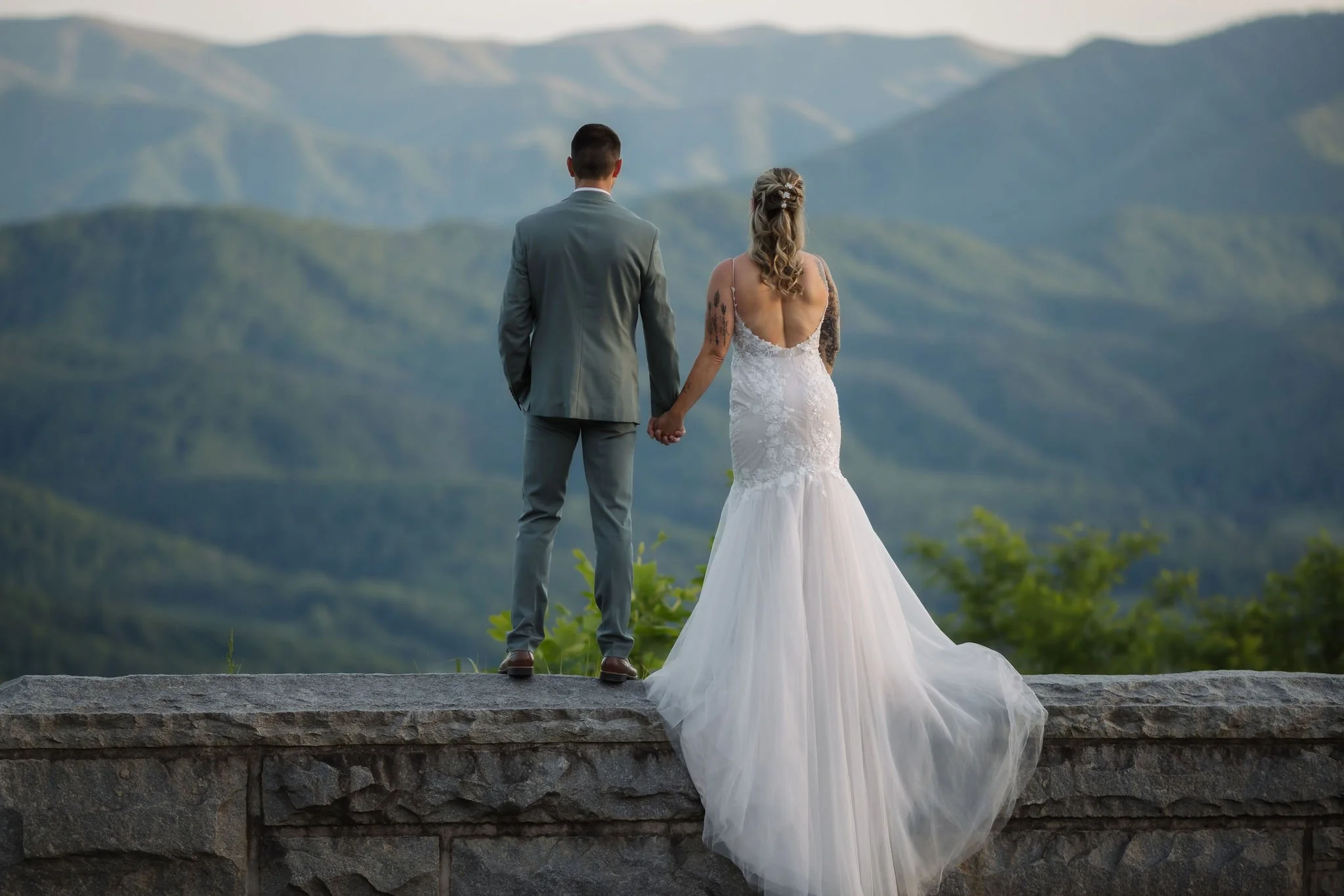 Newlyweds hold hands overlooking layered Smoky Mountain peaks from Foothills Parkway during their Gatlinburg elopement.