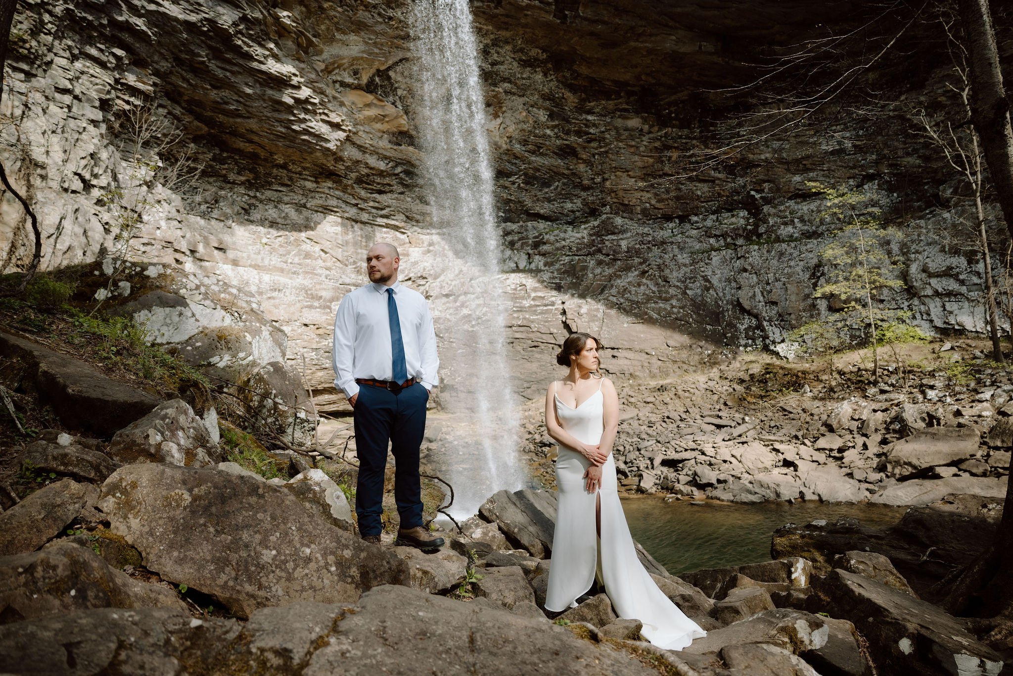 Bride and groom pose among large boulders beneath ozone falls during portraits with their gatlinburg photographer.